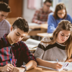 Studenti sedí v lavici a píší text